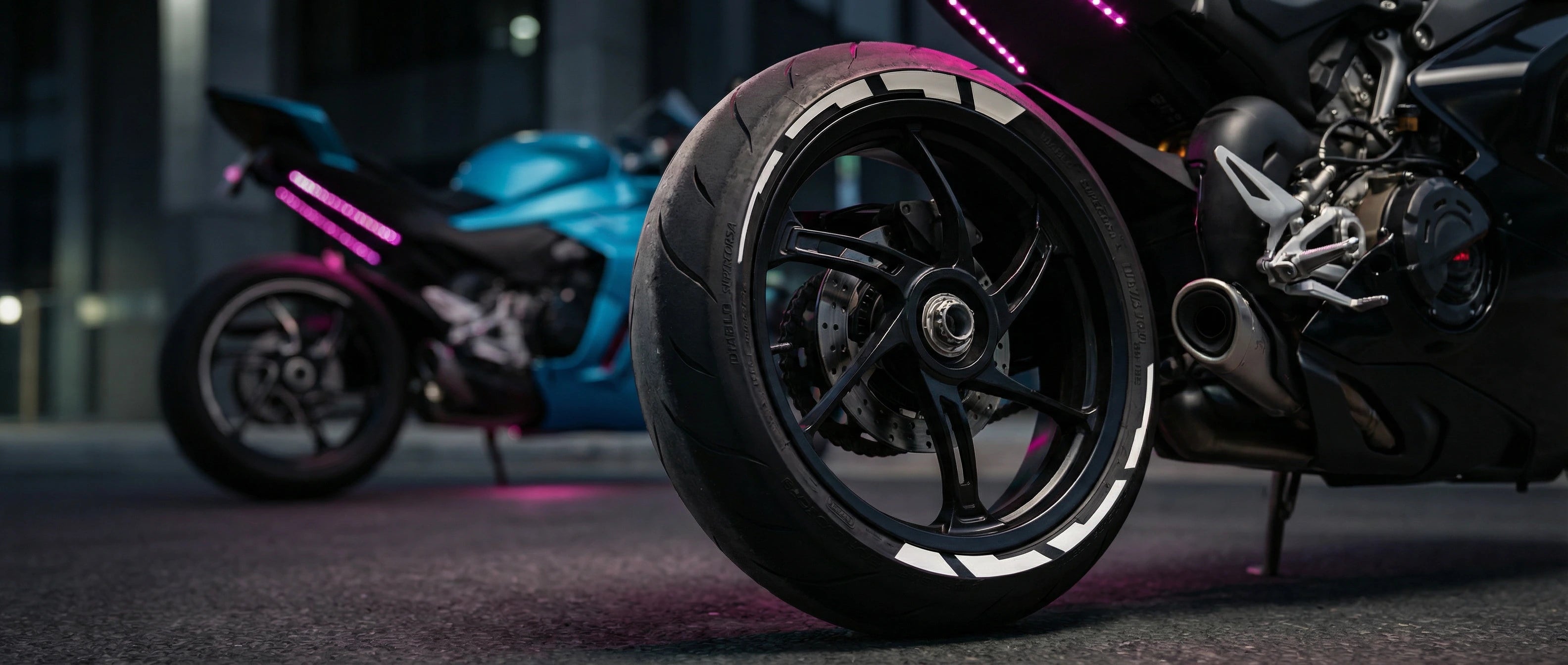 Close-up of a motorcycle wheel with another motorcycle in the background.